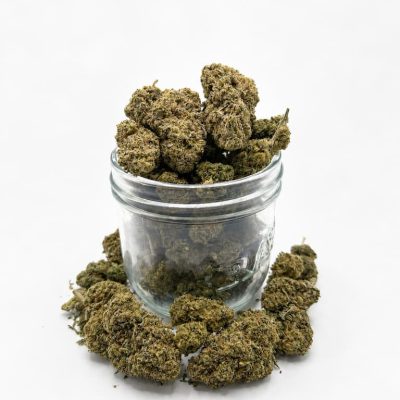 Fleurs CBD Critical Indoor disposées dans et autour d’un pot en verre